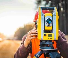 Surveyor operating a total station in the field